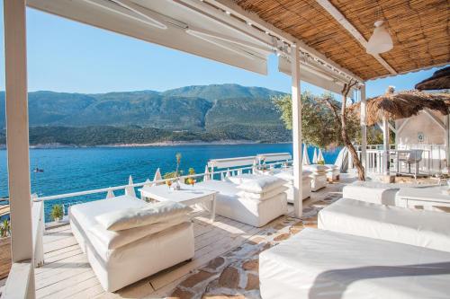 un patio con muebles blancos y vistas al agua en Club Çapa Hotel, en Kas