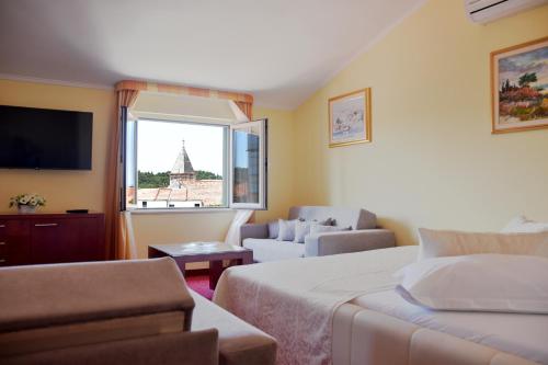 a hotel room with a bed and a couch and a window at Villa Riva in Makarska