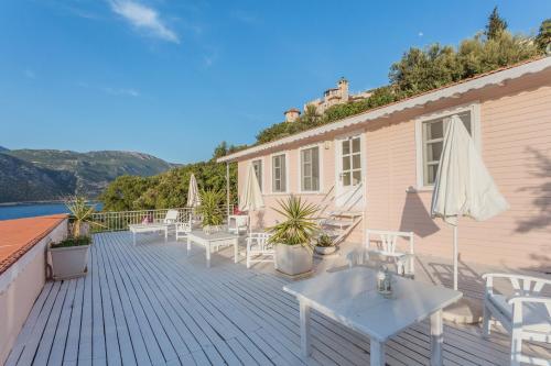 a deck with white tables and chairs and a house at Club Çapa Hotel in Kas