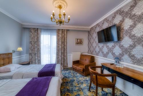 a hotel room with a bed and a desk and a television at Grand Częstochowa in Częstochowa