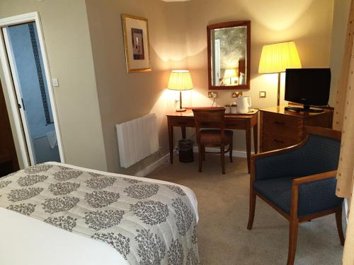 a hotel room with a bed and a desk and a television at Red Lion Hotel in Basingstoke