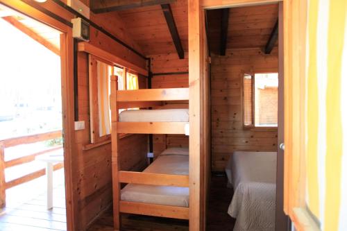 a room with bunk beds in a wooden cabin at Camping Bella Sardinia in S'archittu Cuglieri