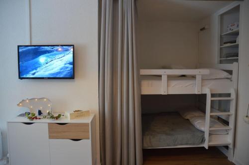 1 dormitorio con litera y TV en la pared en Charmant studio cabine COCOON à 100 m des pistes, en Chamrousse