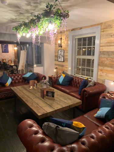 a living room with leather couches and a wooden table at Strawberry Bank Hotel, NEC in Meriden