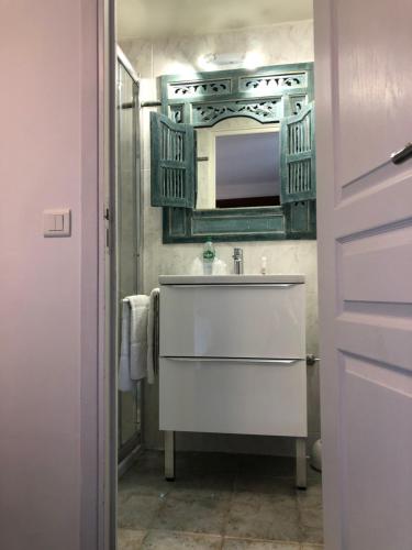 La salle de bains est pourvue d'un lavabo blanc et d'un miroir. dans l'établissement Hôtel Génépi, à Beuil