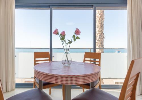 eine Vase mit Blumen auf einem Tisch vor einem Fenster in der Unterkunft Apartamentos Varadero Sea View & Spa in La Cala del Moral