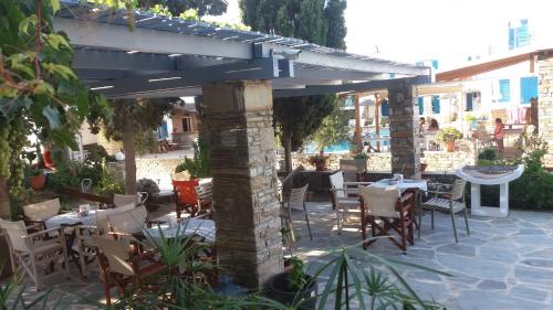 a patio with tables and chairs under a pergola at Ioanna Apartments in Agios Prokopios