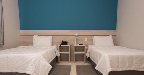 two beds in a room with a blue wall at Nova Hotel in Ciudad del Este