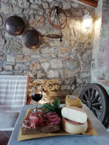 a table with a plate of cheese and a glass of wine at B&B CASAGRANDE in Quercegrossa