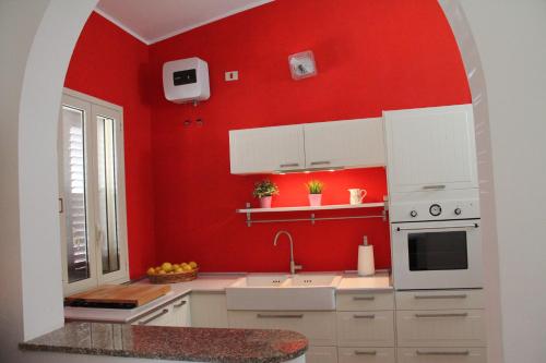 a kitchen with red walls and white cabinets at Villa Carmela Arenella in Arenella