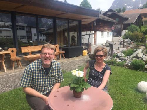 Ein Mann und eine Frau sitzen an einem Tisch mit einer Blumenvase in der Unterkunft Chalet Grünegg in Grindelwald