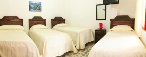 a group of three beds in a room with white sheets at Hotel La Casona in Jardin