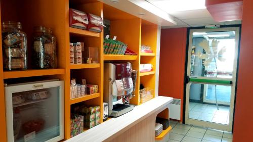 a room with orange walls and shelves with food at Premiere Classe Périgueux - Boulazac in Boulazac