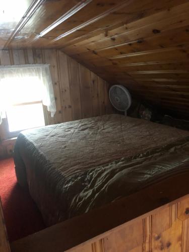 a bed in a log cabin with a window at Welcome to the Lake in Northwood