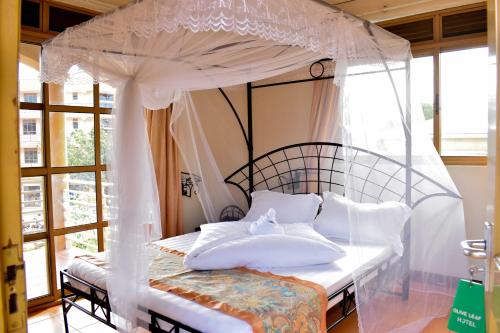 a bedroom with a canopy bed with white pillows at Rates Hotel Mbale in Mbale