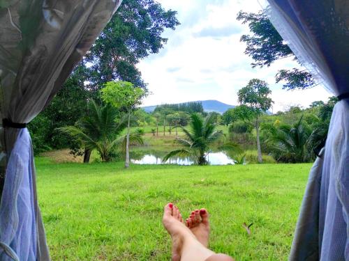 a person with their feet up in a tent in a field at The Creek Villa in Loei
