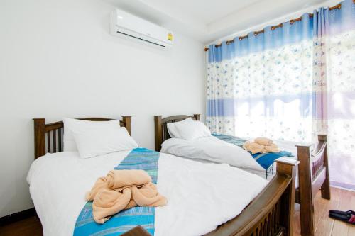 two beds with towels on them in a bedroom at The Creek Villa in Loei