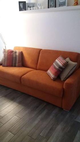 an orange couch sitting in a living room with two pillows at Como Via Carcano 13 in Como