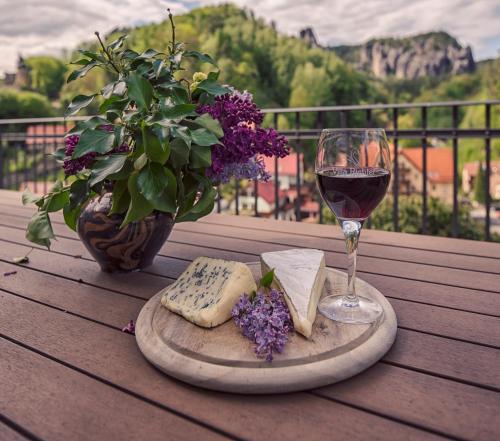 a table with a glass of wine and cheese and flowers at Villa Richter in Kurort Rathen