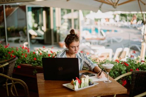 a woman sitting at a table with a laptop at Hotel Premier Aqua - Adults Only in Vrdnik