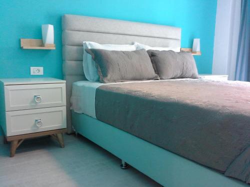 a blue bedroom with a bed and a night stand at Gala Apartment in Nea Potidaea
