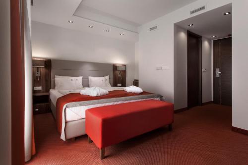 a bedroom with a large bed and a red ottoman at Bükkös Hotel & Spa in Szentendre