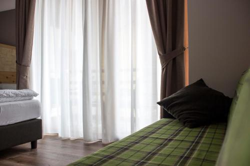 a bed with a pillow sitting next to a window at DolceVita Ambiez B&B in San Lorenzo in Banale