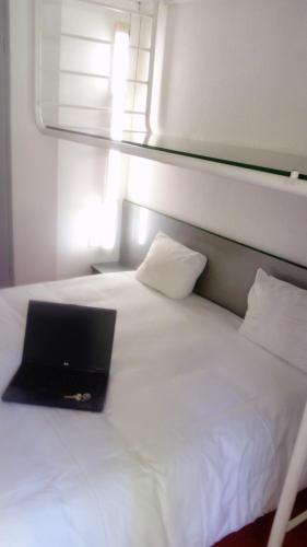 a laptop computer sitting on top of a white bed at Premiere Classe Périgueux - Boulazac in Boulazac