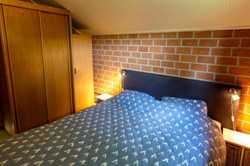 een blauw bed in een kamer met een bakstenen muur bij Kruisselbrink in Winterswijk