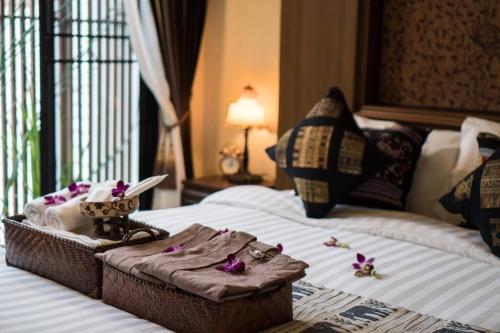 a basket on a bed with purple flowers on it at Wannamas Chiangmai Boutique House in Chiang Mai