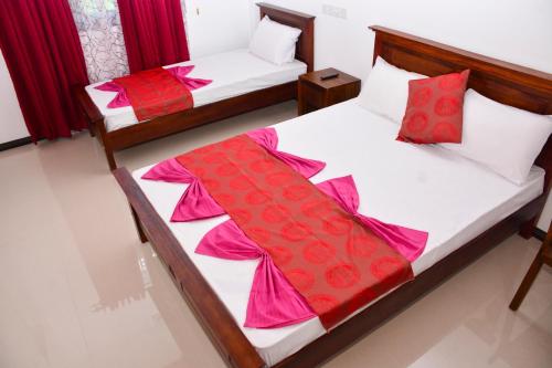 two beds in a room with red and white sheets at Brisa Marina in Negombo
