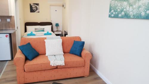 a living room with a orange couch with blue pillows at TUii Appart, Cleveleys Road Holbeck in Leeds