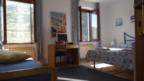 a bedroom with two beds and a desk with a computer at La camera del mulino in Levanto