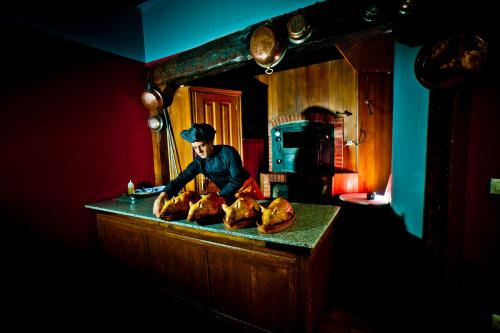 a man standing in a kitchen with chickens on a counter at Hotel Condes de Castilla in Segovia