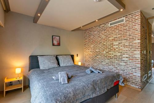 a bedroom with a large bed with a brick wall at René in Lichtervelde