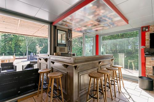 a bar with stools in a kitchen with windows at René in Lichtervelde