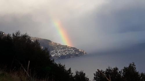 a rainbow over a body of water with a mountain at Le Muse Suite in Sorrento