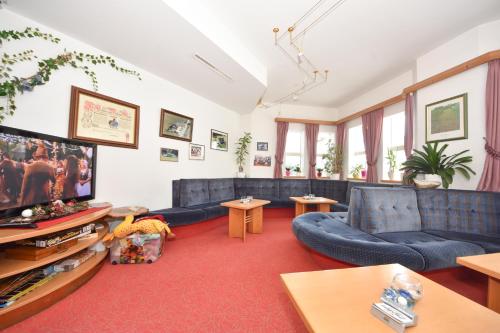 a living room with blue couches and a flat screen tv at Gasthof Martha in Nauders