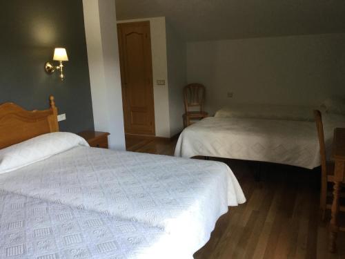 a hotel room with two beds with white sheets at Hotel Cinco Castaños in Candelario