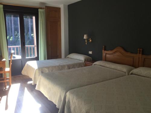 a bedroom with two beds and a window at Hotel Cinco Castaños in Candelario