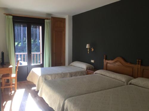 a hotel room with two beds and a window at Hotel Cinco Castaños in Candelario
