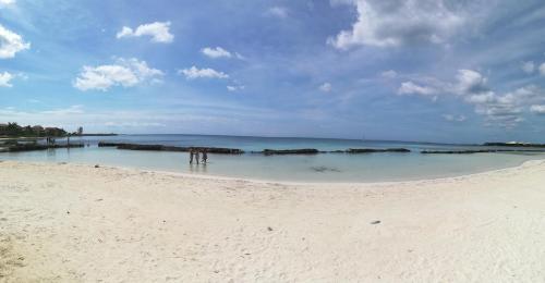 a group of people standing in the water on a beach at Villas Picalu Studios & Suites in Puerto Aventuras
