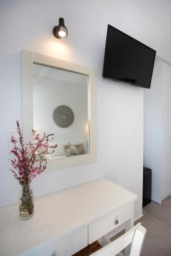 a white room with a mirror and a vase with flowers at Kouros Village in Antiparos Town