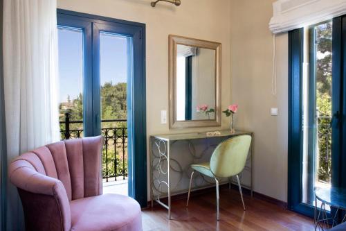 a living room with a chair and a table and windows at Avra Private Suites in Lassi