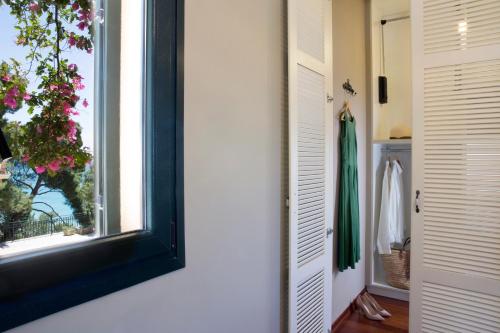 a room with a window and a door with a robe at Avra Private Suites in Lassi