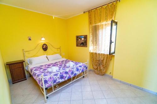 1 dormitorio con cama y pared amarilla en Villa Mapa - Appartamenti vicino al mare, en Vieste