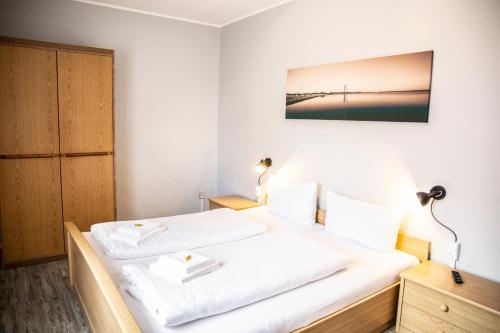 a bedroom with a bed with two white sheets at Hotel Tum Stüürmann in Büsum