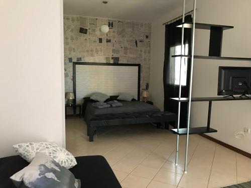 a living room with a bed and a television at Blue Eagle Guesthouse - Casa de hospedes in Santa Maria