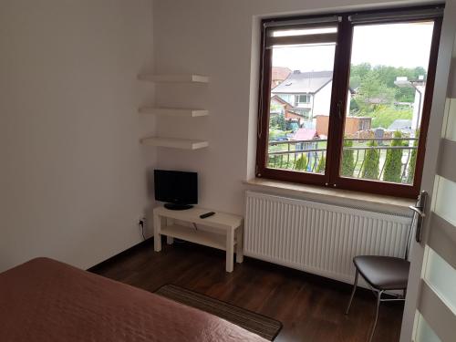 1 dormitorio con 1 cama, TV y ventana en Villa Amber, en Międzywodzie