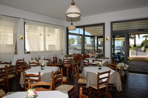 um restaurante com mesas e cadeiras brancas e janelas em Hotel Ristorante Milton em Varazze